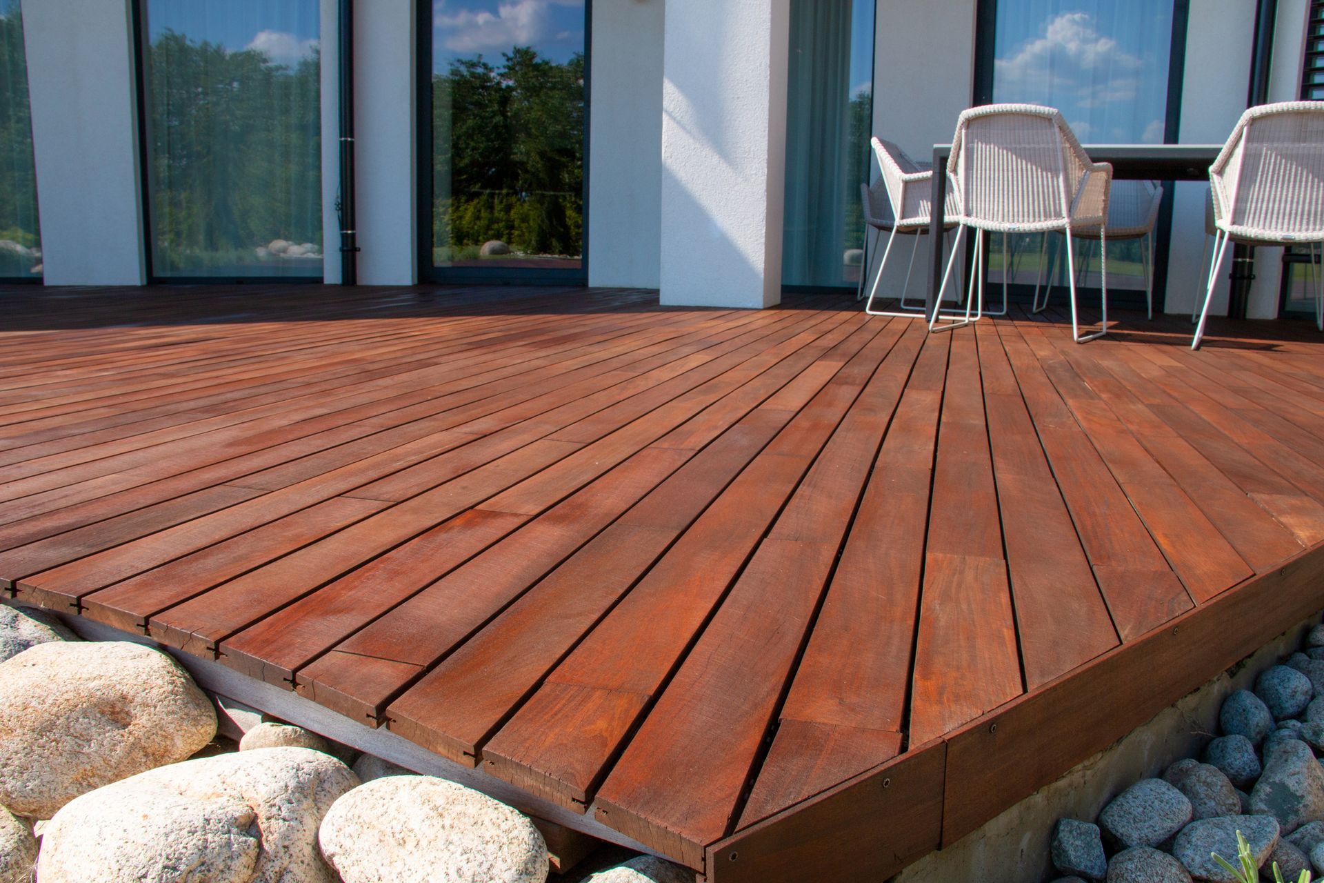 Wooden deck with patio furniture and stone landscaping.