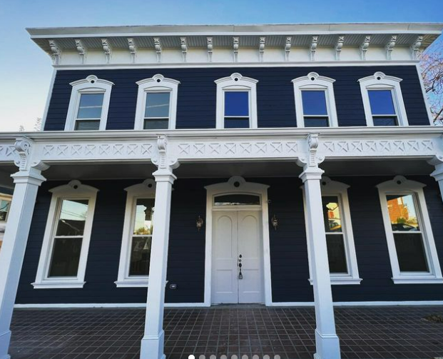 Two-story, navy blue house with white trim. A front porch with columns, multiple windows, and a white door.