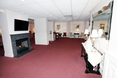 Spacious living room with red carpet, fireplace, TV, and white furniture in a bright, open layout