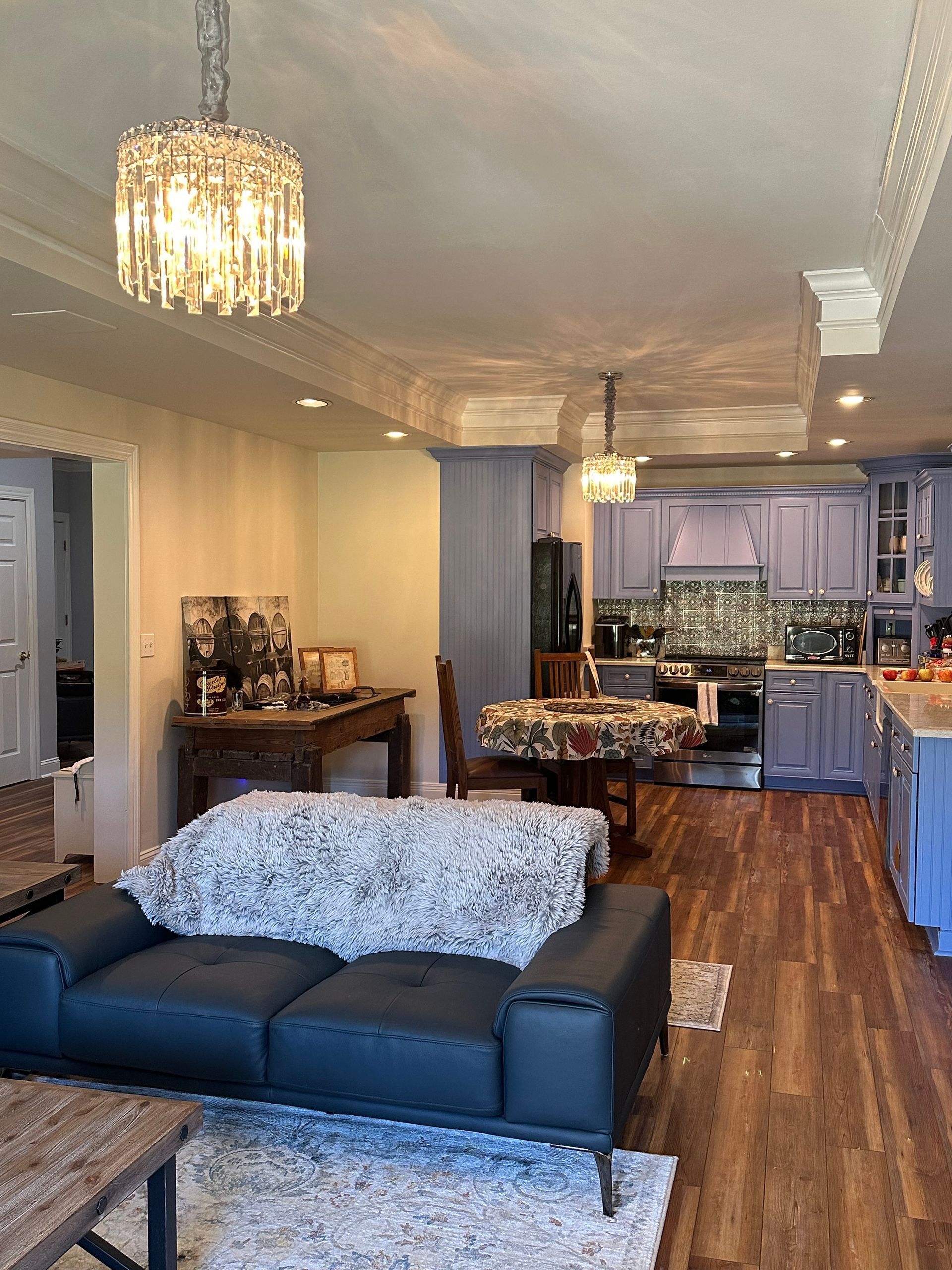 A living room with a black couch and a chandelier hanging from the ceiling.