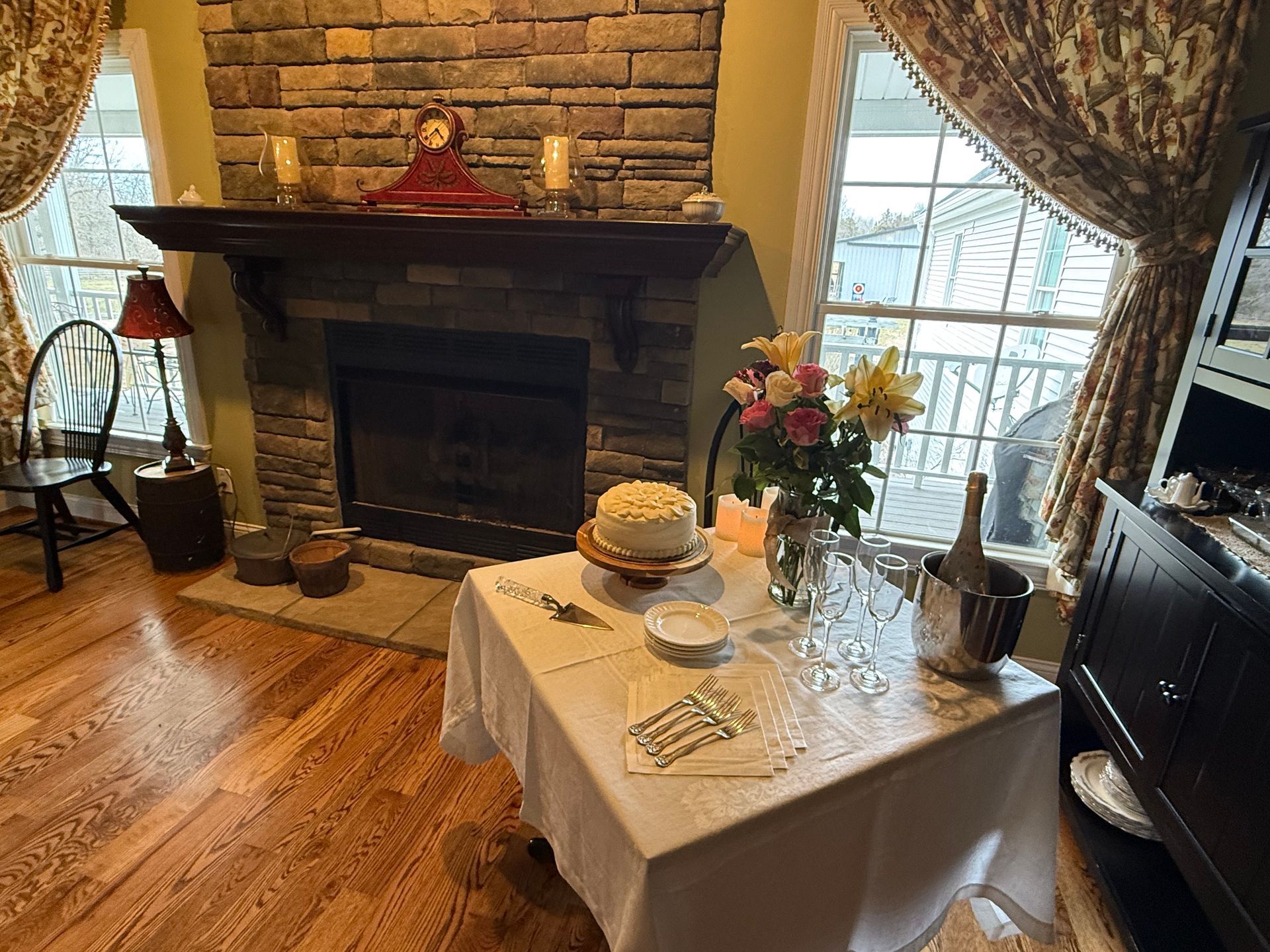 There is a table with a cake on it in front of a fireplace.