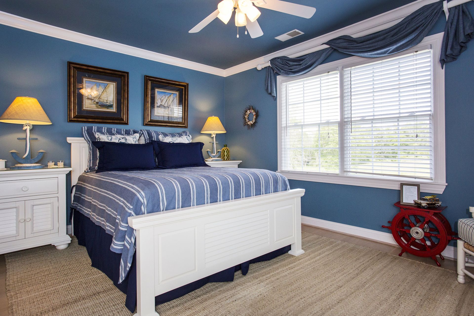 Bedroom with blue walls, white trim, bed with blue and white striped bedding, and nautical decor.