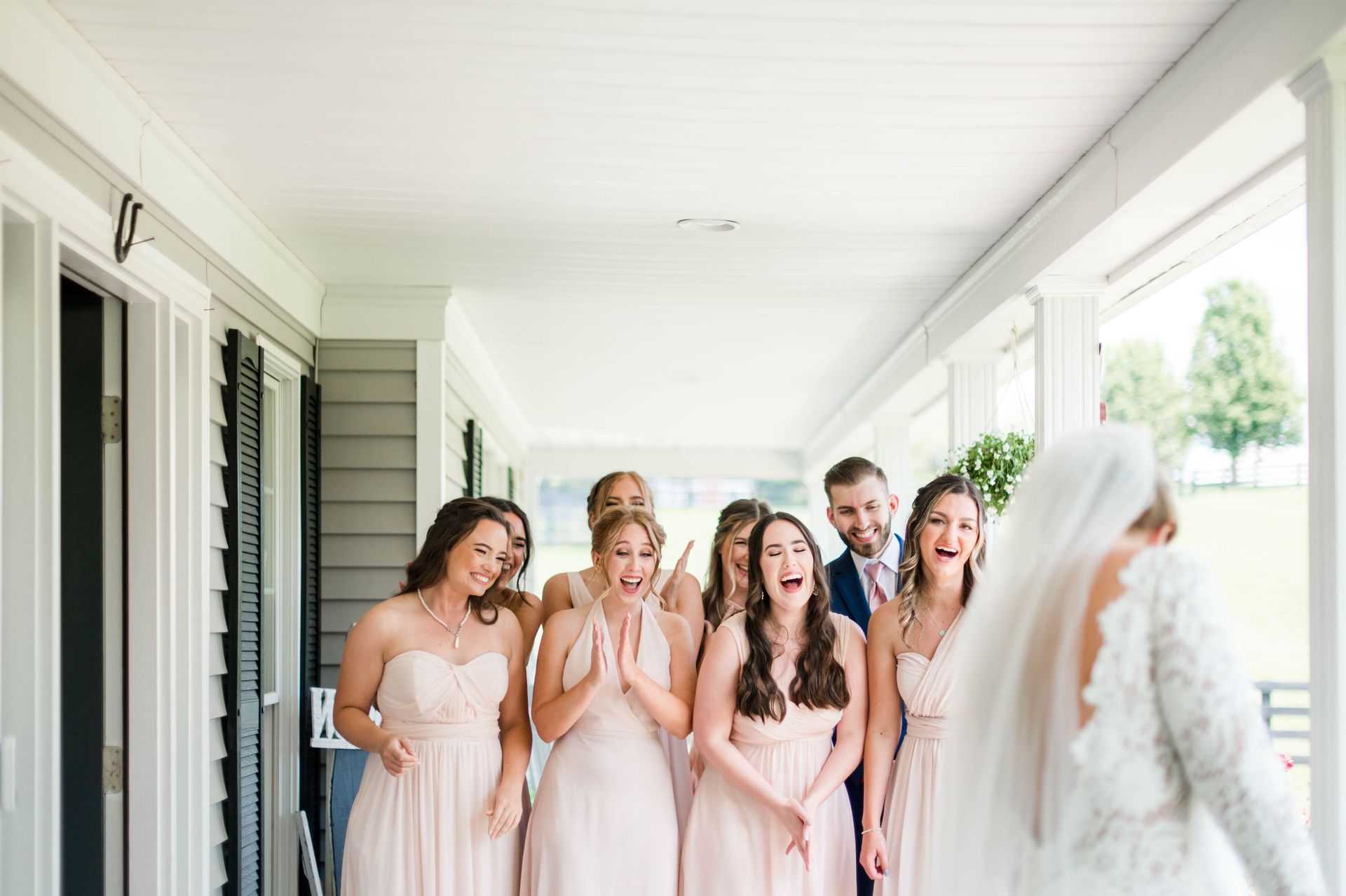 A bride and her bridesmaids are standing on a porch.