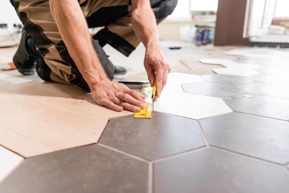 A Man Is Kneeling On The Floor While Installing Tiles — Tall Orders Port Macquarie In Port Macquarie, NSW 