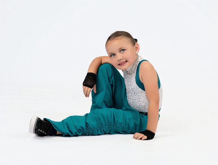 A young girl is wearing a yellow tank top and black pants