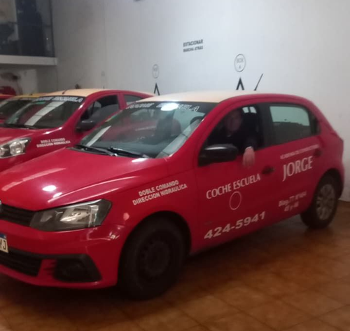 Manos agarrando el volante de un coche desde el interior, con una manga roja a la vista.