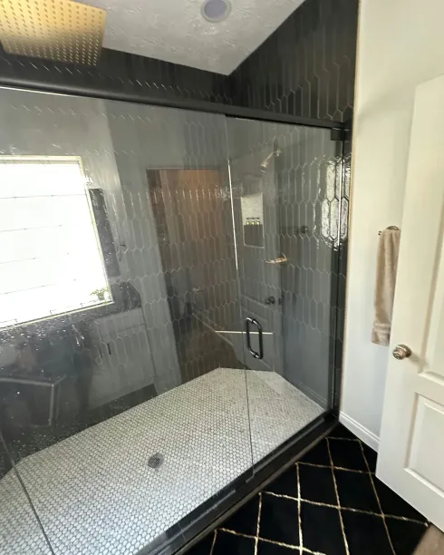 Small bedroom with a mesh-covered bed, window, white door, and black-and-gold patterned rug.