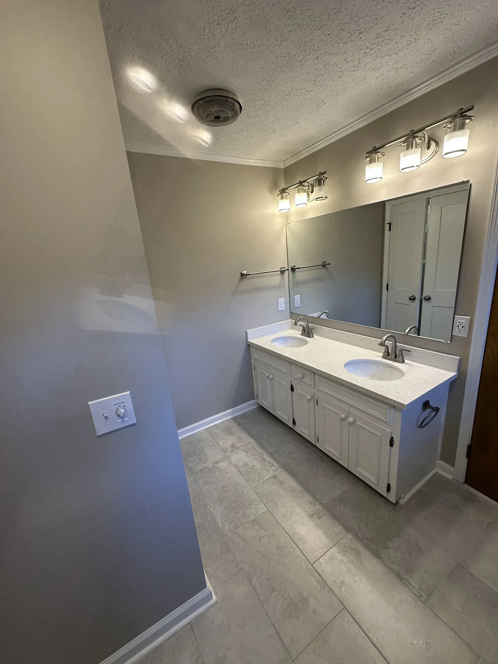 Bright bathroom with double vanity, large mirror, and gray walls and floor.