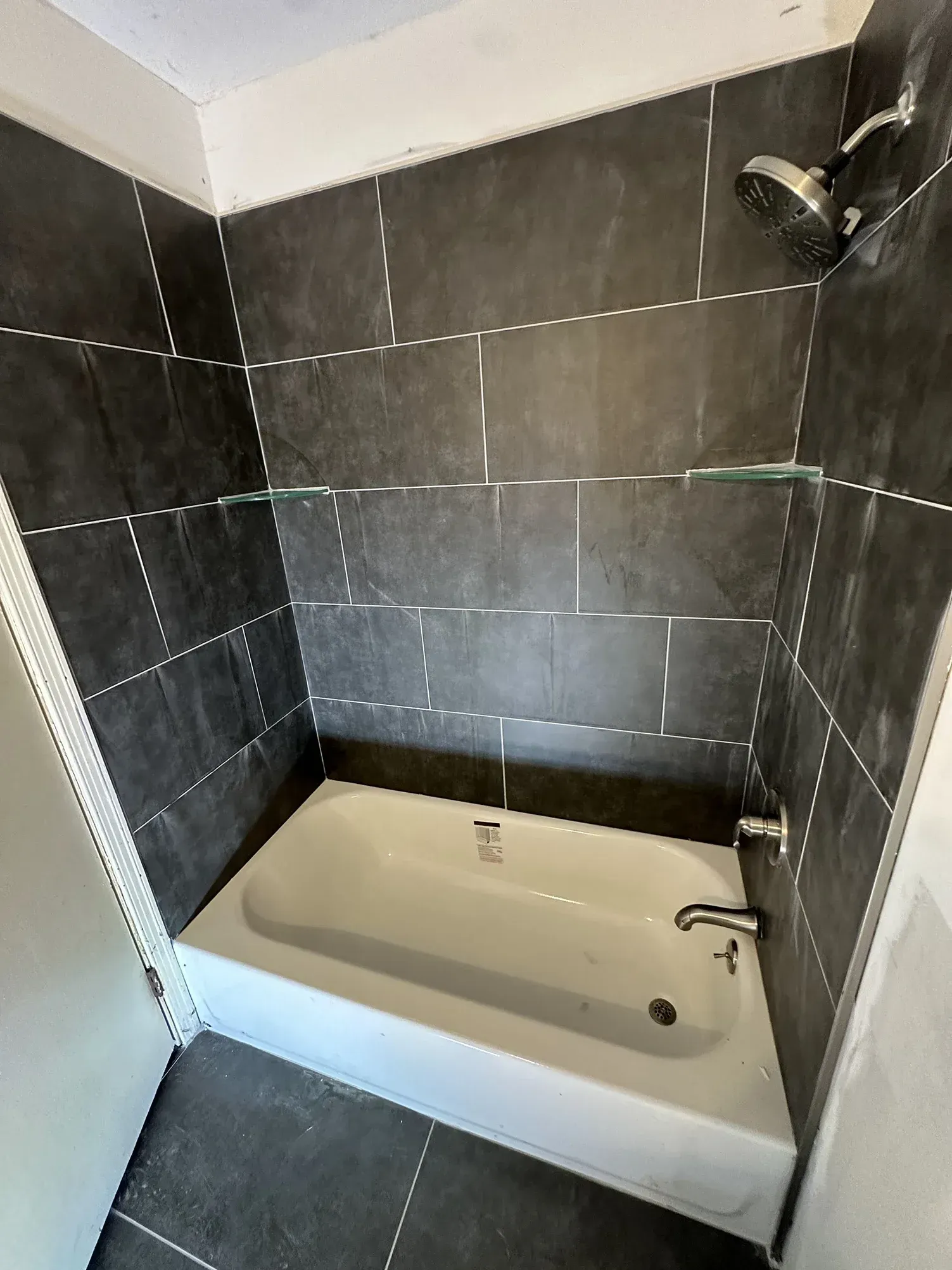 Small bathroom with a tiled shower-tub combo and handheld showerhead.