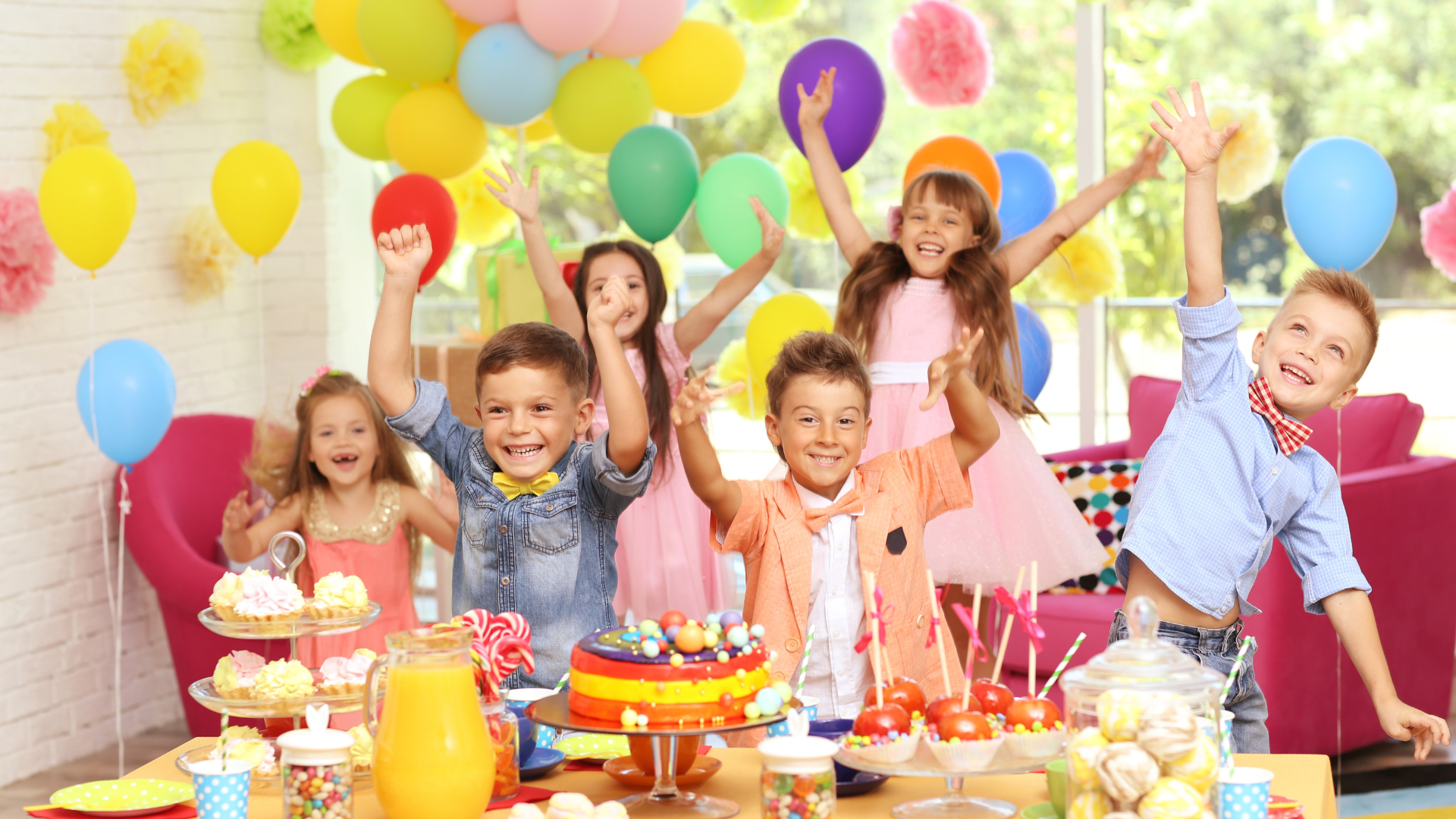Children at a birthday party, smiling with balloons, cake, and colorful drinks on a decorated table