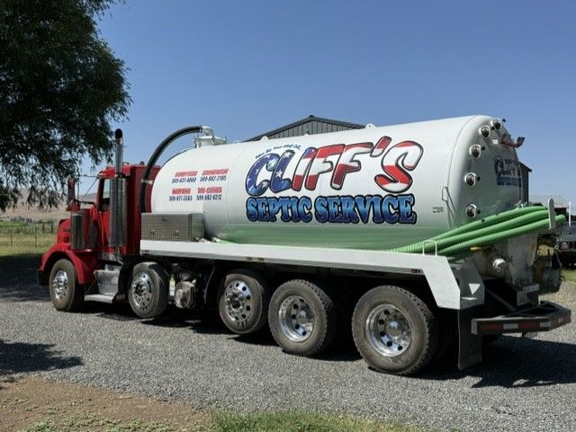 Red and white Cliff’s septic service tanker truck parked on gravel outdoors