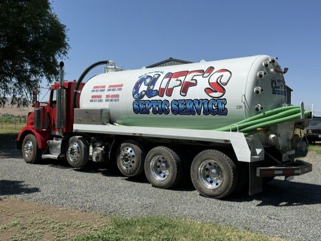 Orange tanker truck pumping liquid through a hose into a field outlet