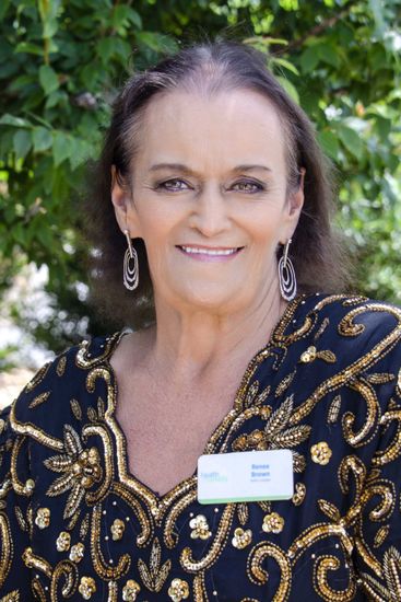 A woman in a black and gold dress is smiling for the camera.