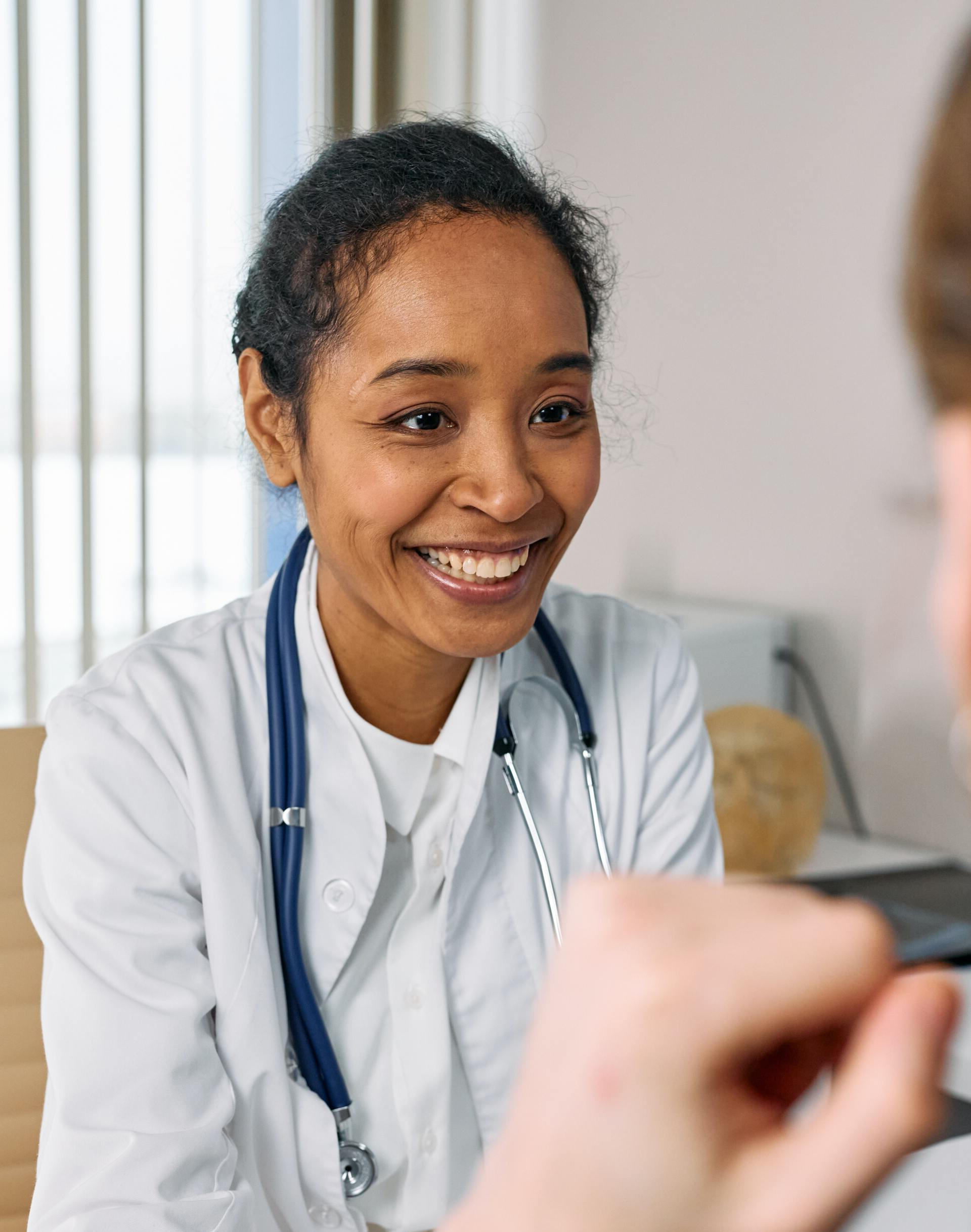 A female doctor is smiling while talking to a patient.