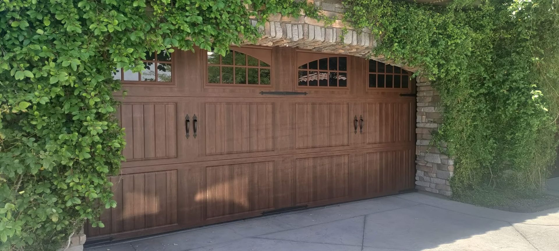 A large wooden garage door is surrounded by ivy.