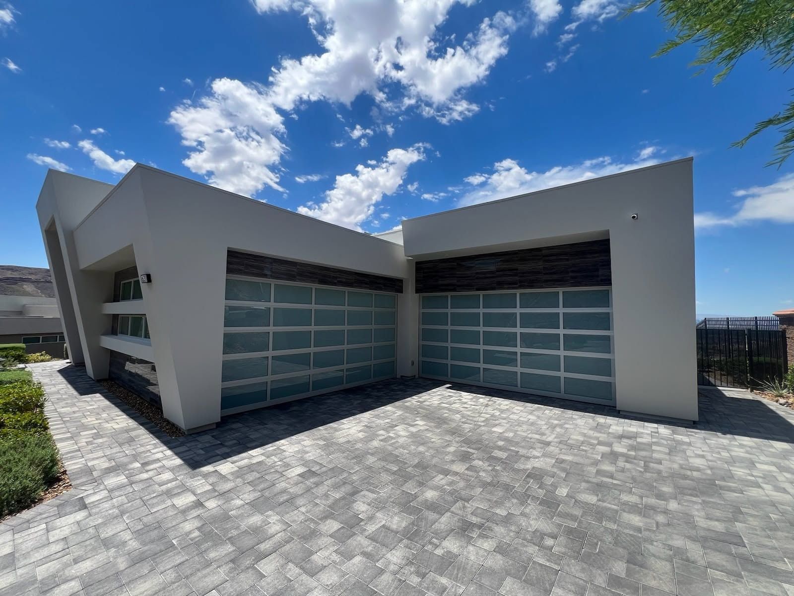 A modern house with two garage doors and a brick driveway.