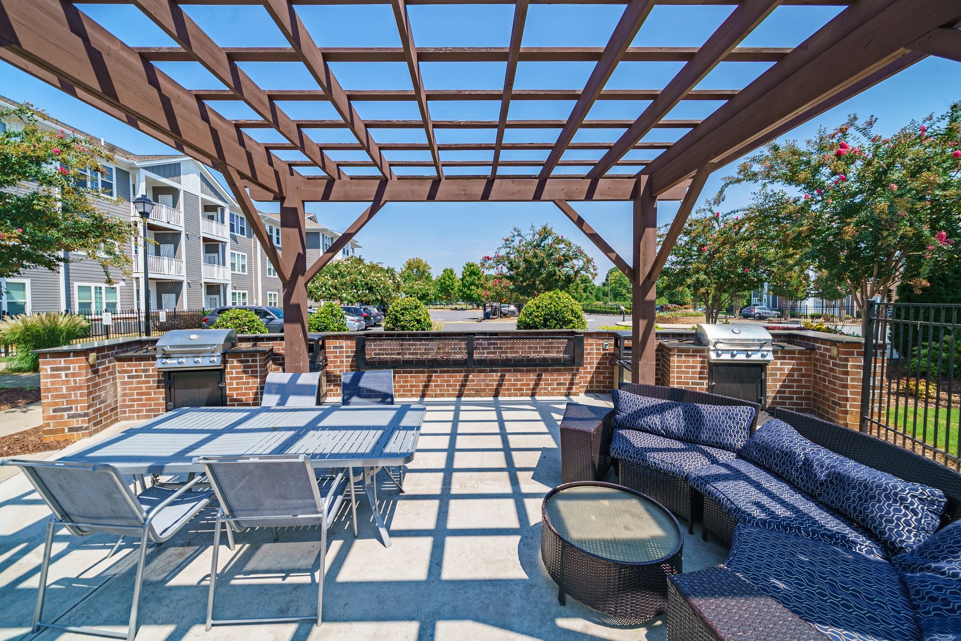 Outdoor patio with a pergola, grills, seating, and a dining table at Willows at Fort Mill, offers apartments in Fort Mill, SC.