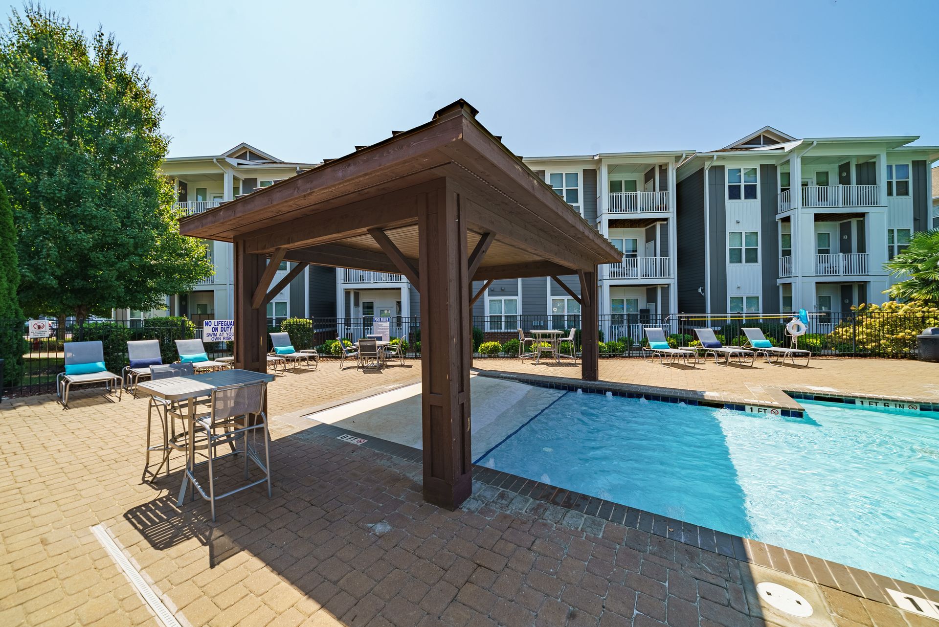 Poolside cabana beside a resort swimming pool with lounge chairs and apartment buildings in the background at Willows at Fort Mill apartments for rent in SC.