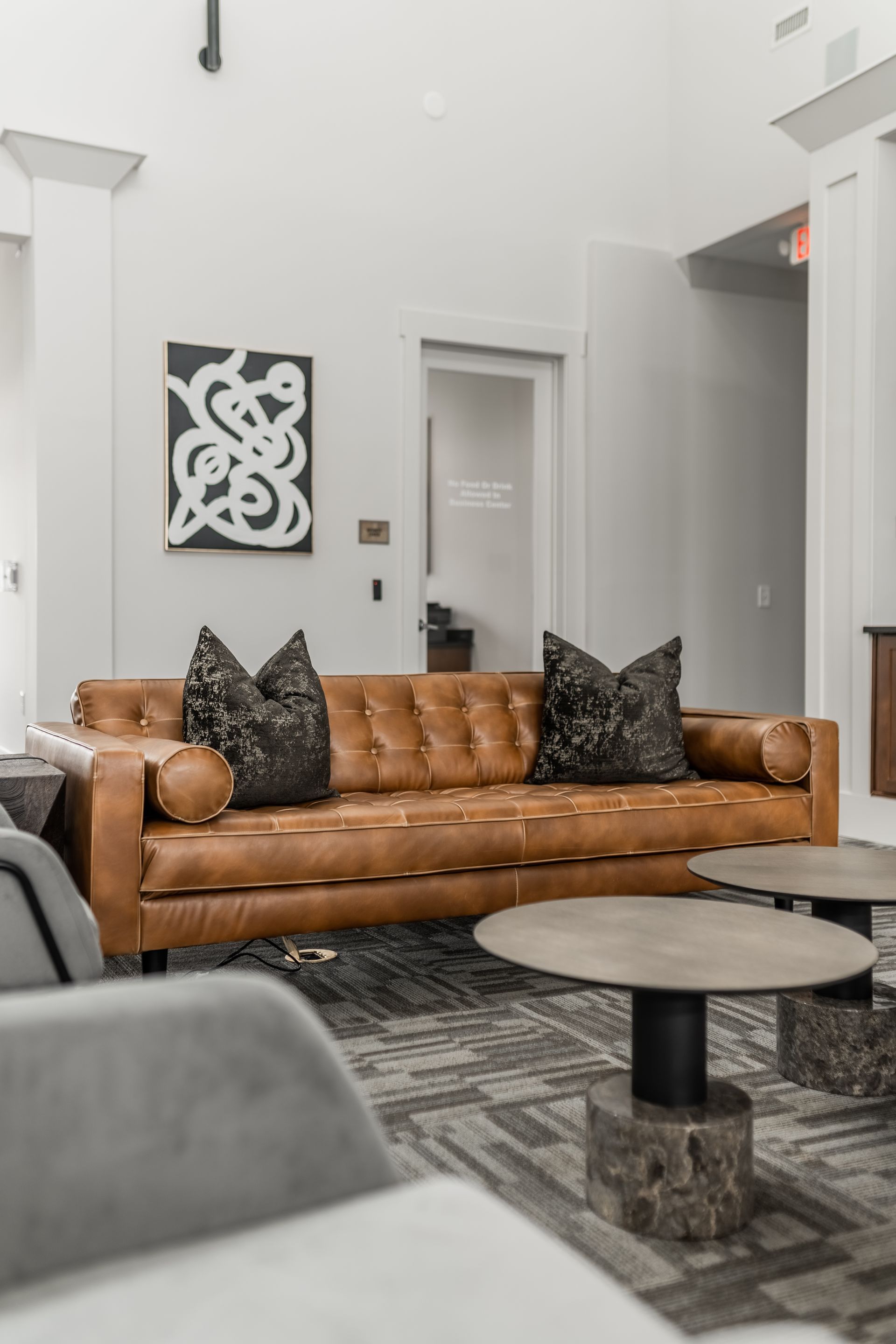 Brown leather sofa with decorative pillows in a modern clubhouse at Willows at Fort Mill, offers apartments for rent in Fort Mill, SC.