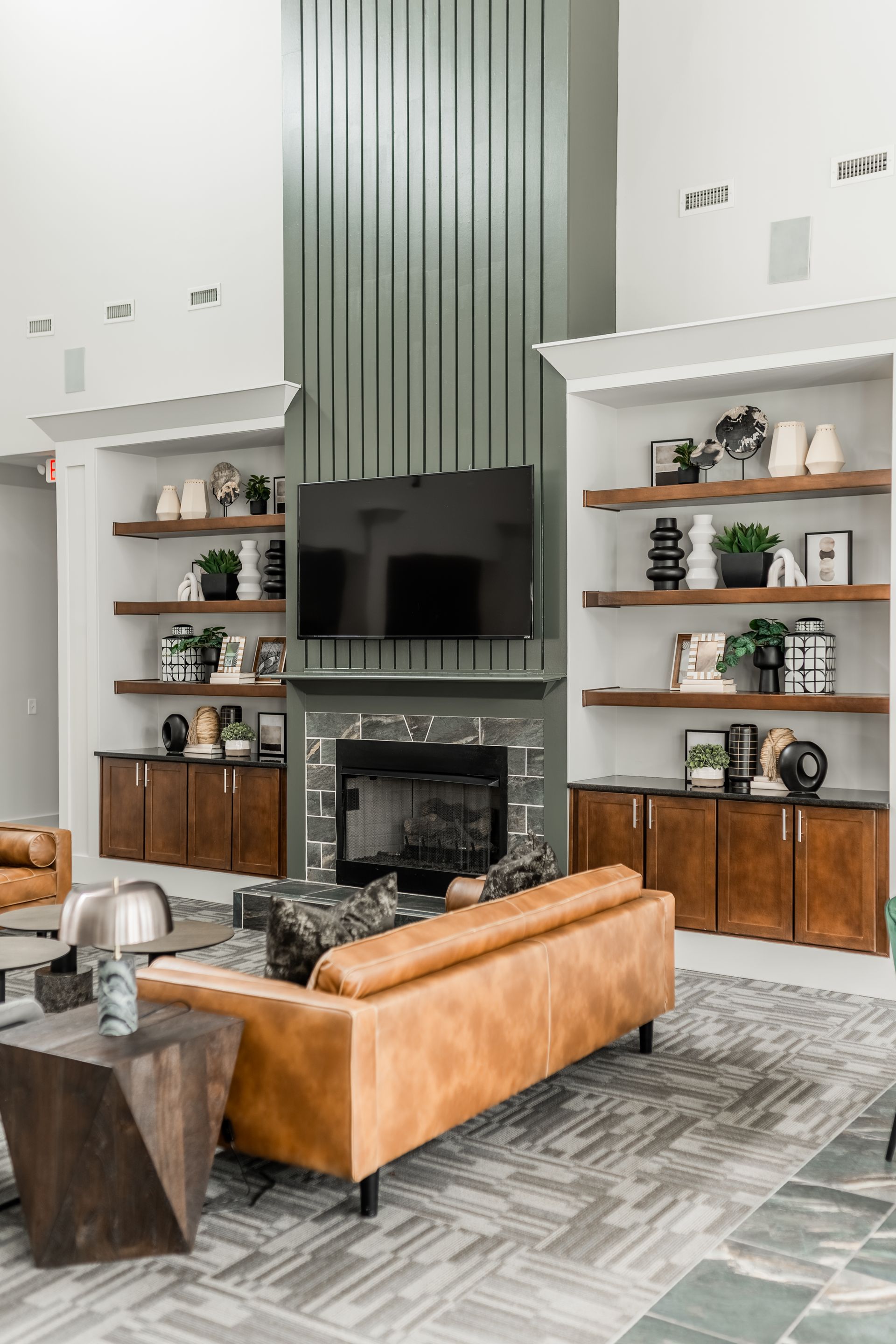 Modern living room with a tan sofa, built-in shelves, black fireplace, and large TV against a white wall at Willows at Fort Mill apartments for rent in SC.