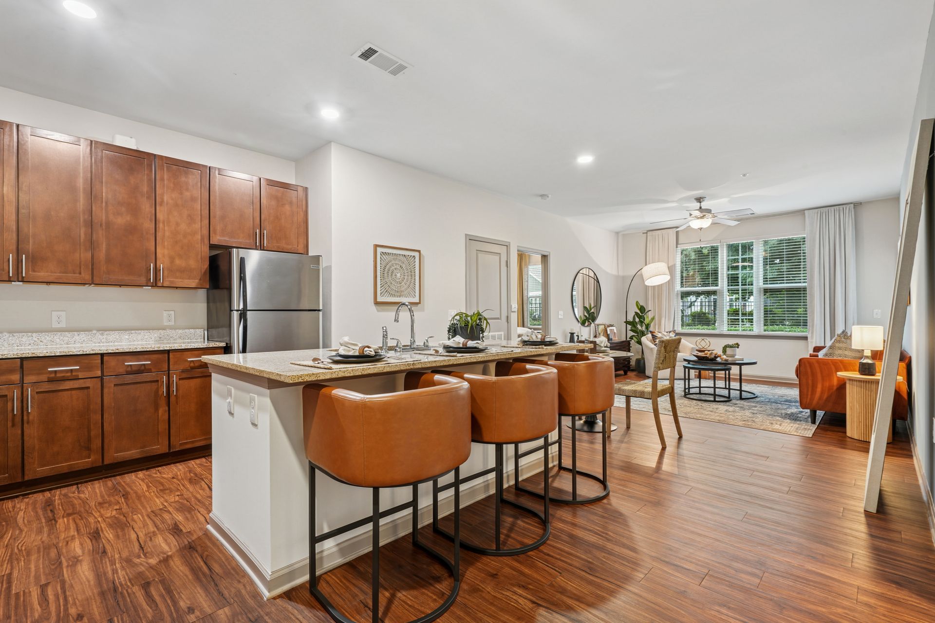 Modern kitchen and open dining area with wood floors, white walls, island seating, and large windows at Willows at Fort Mill apartments for rent in SC.