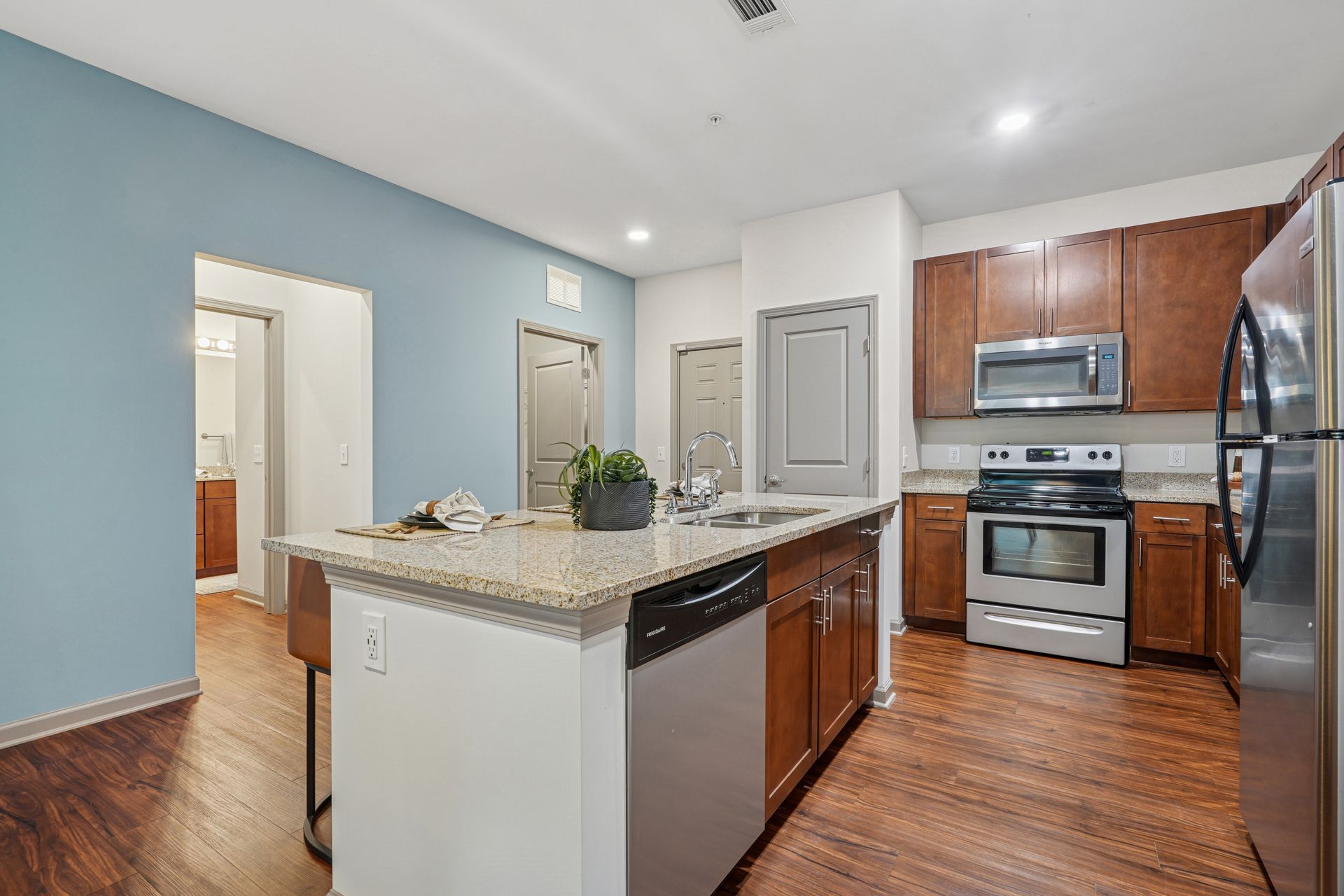 Modern kitchen with granite island, wood cabinets, stainless steel appliances, and hardwood floors at Willows at Fort Mill apartments for rent in SC.