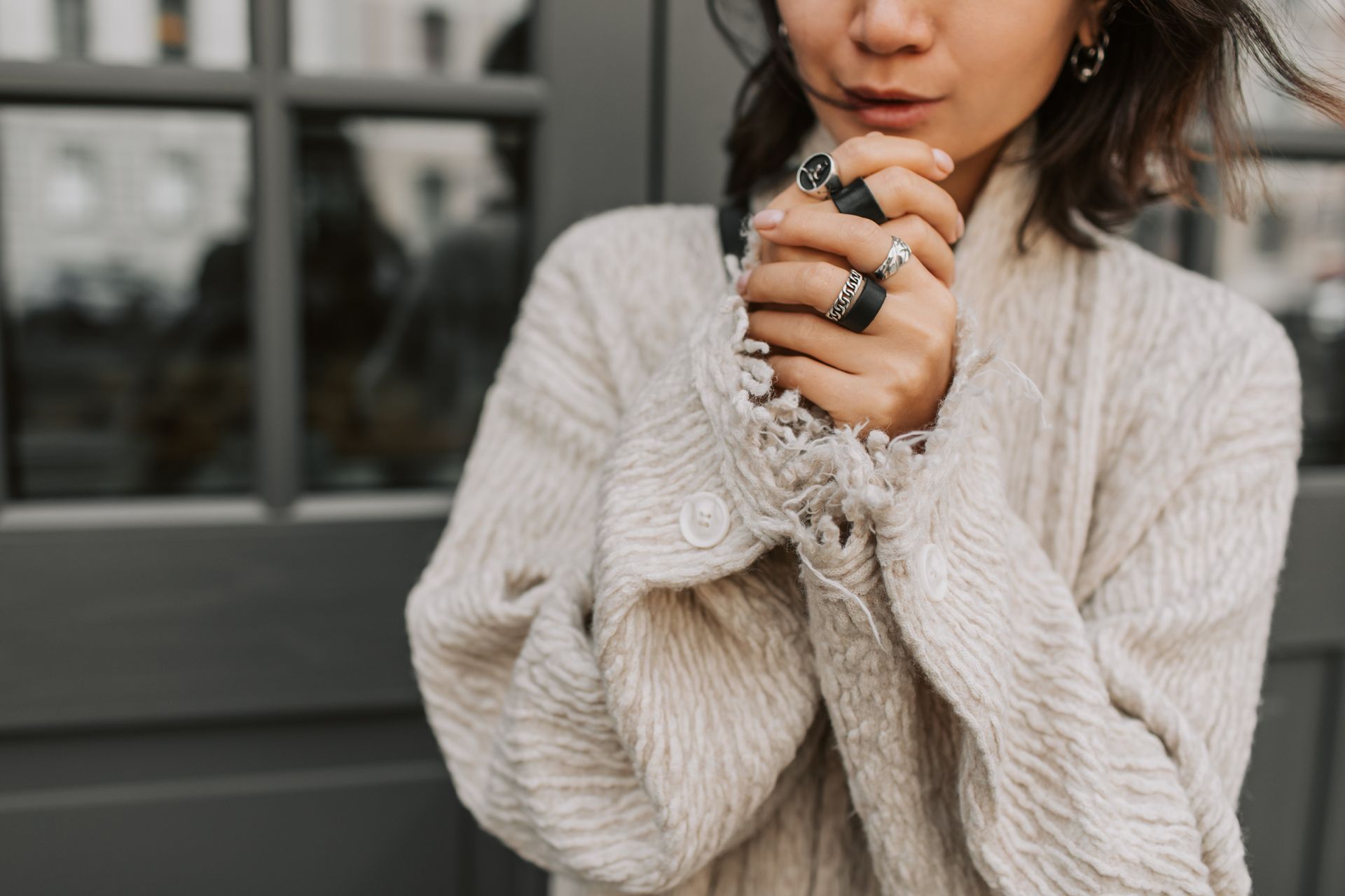 A woman in a sweater is holding a cup of coffee in her hands.