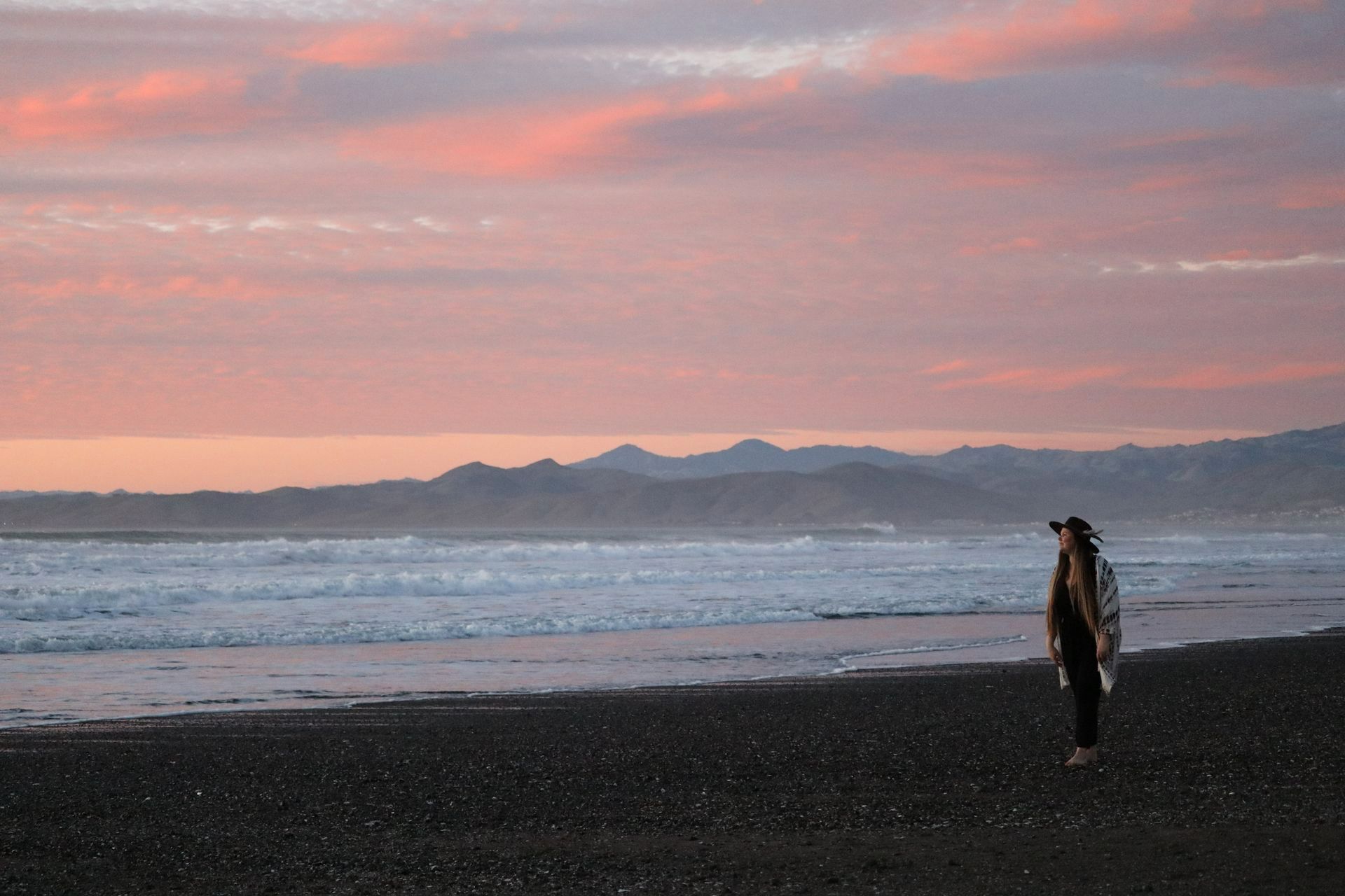 A person standing on a beach looking at the ocean