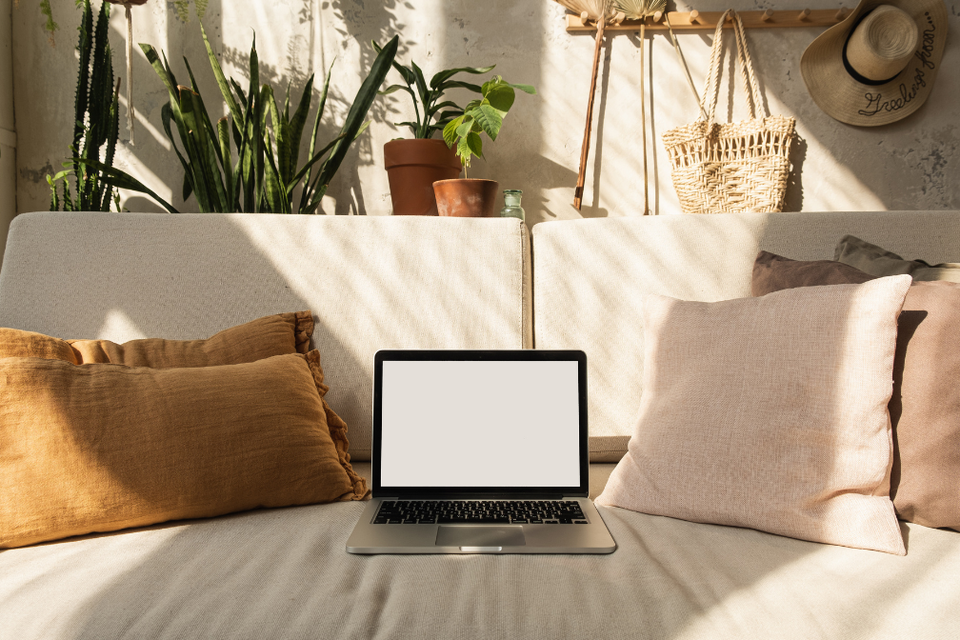 A laptop computer is sitting on a couch in a living room.