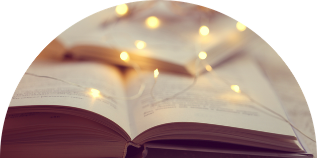 A close up of an open book with a string of lights in the background.