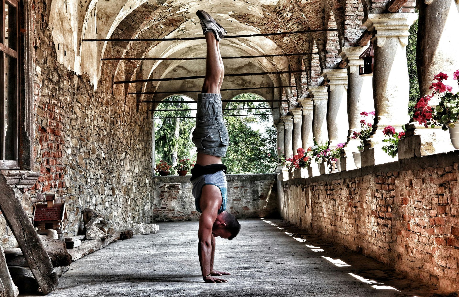 A man is doing a handstand in a stone hallway.