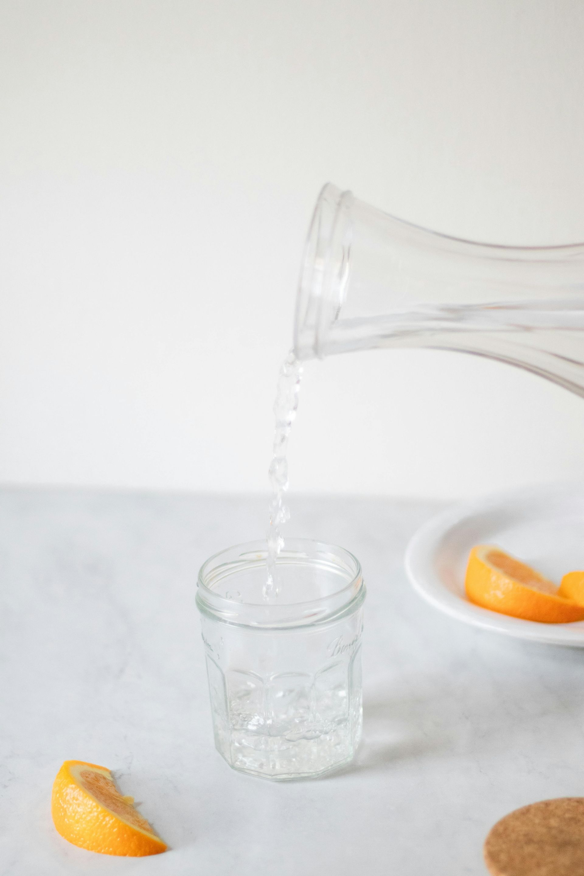 A glass of water is being poured from a pitcher into a glass.