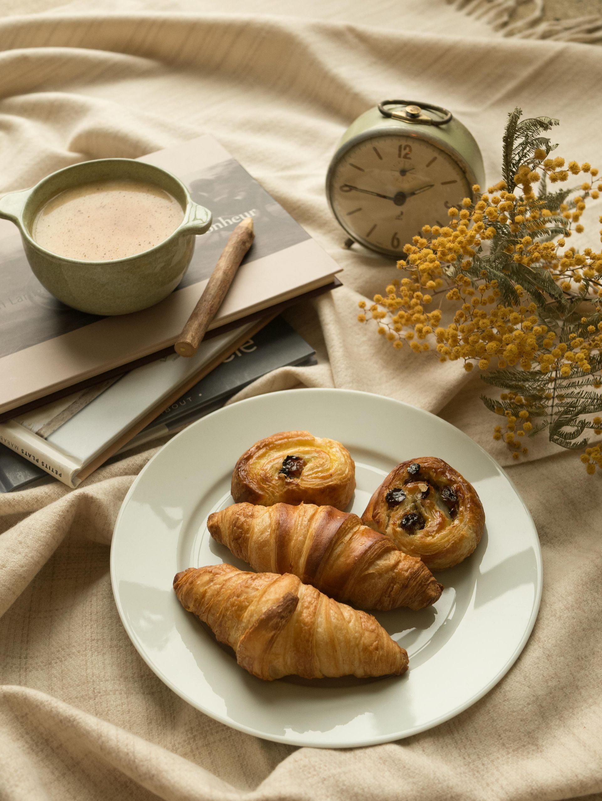 A plate of pastries and a cup of coffee on a blanket.