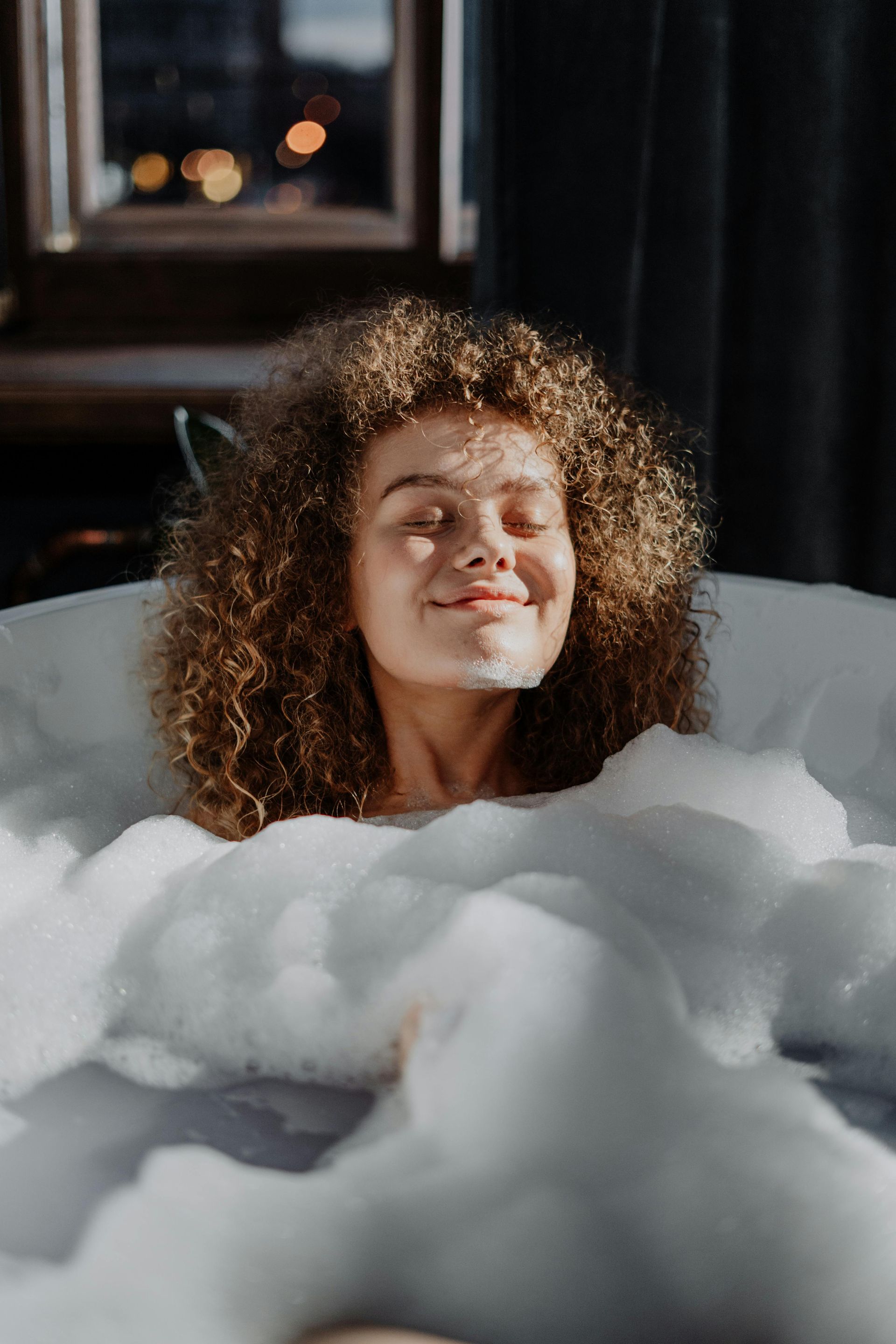 A woman is taking a bath in a bathtub filled with foam.