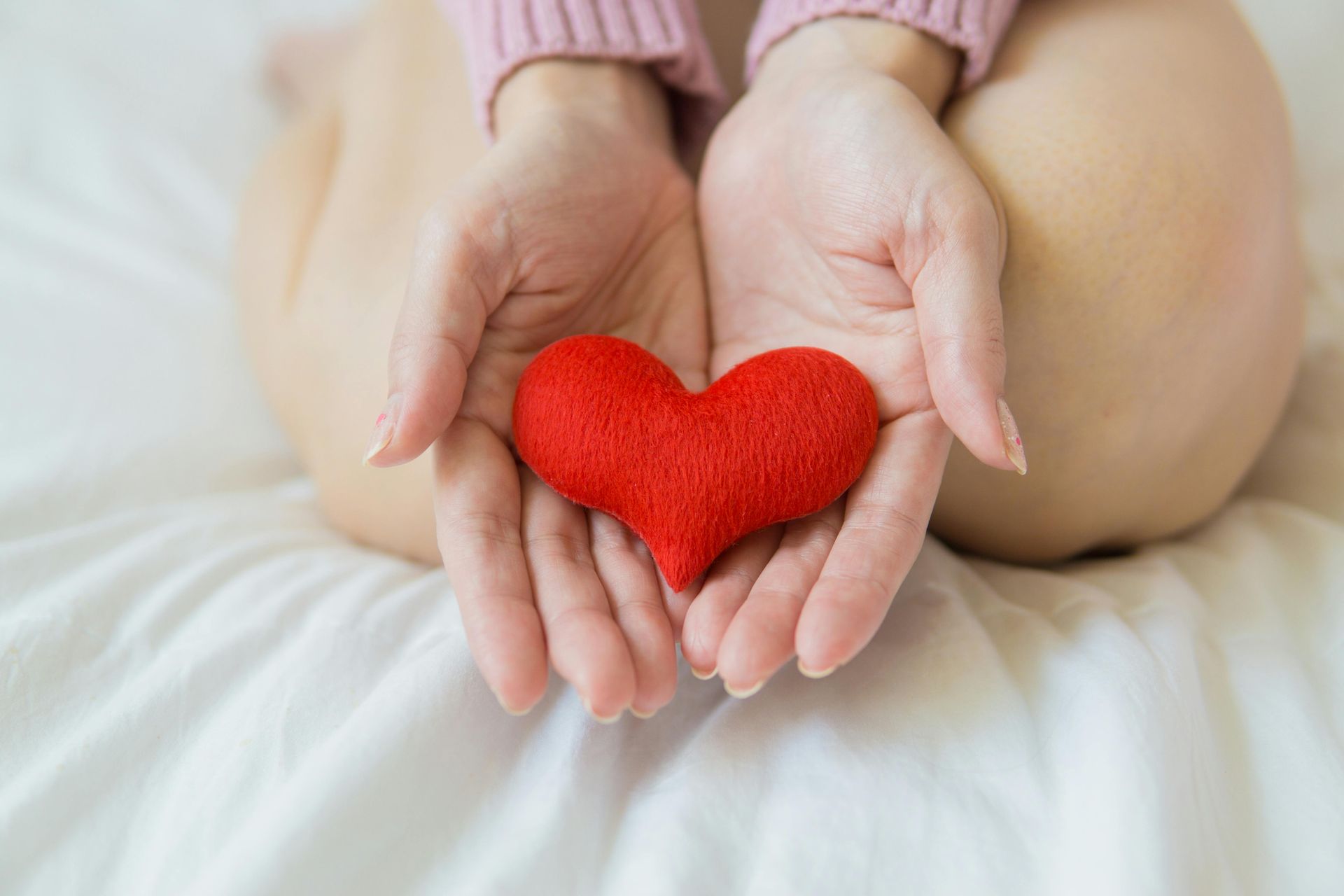 A woman is holding a red heart in her hands.