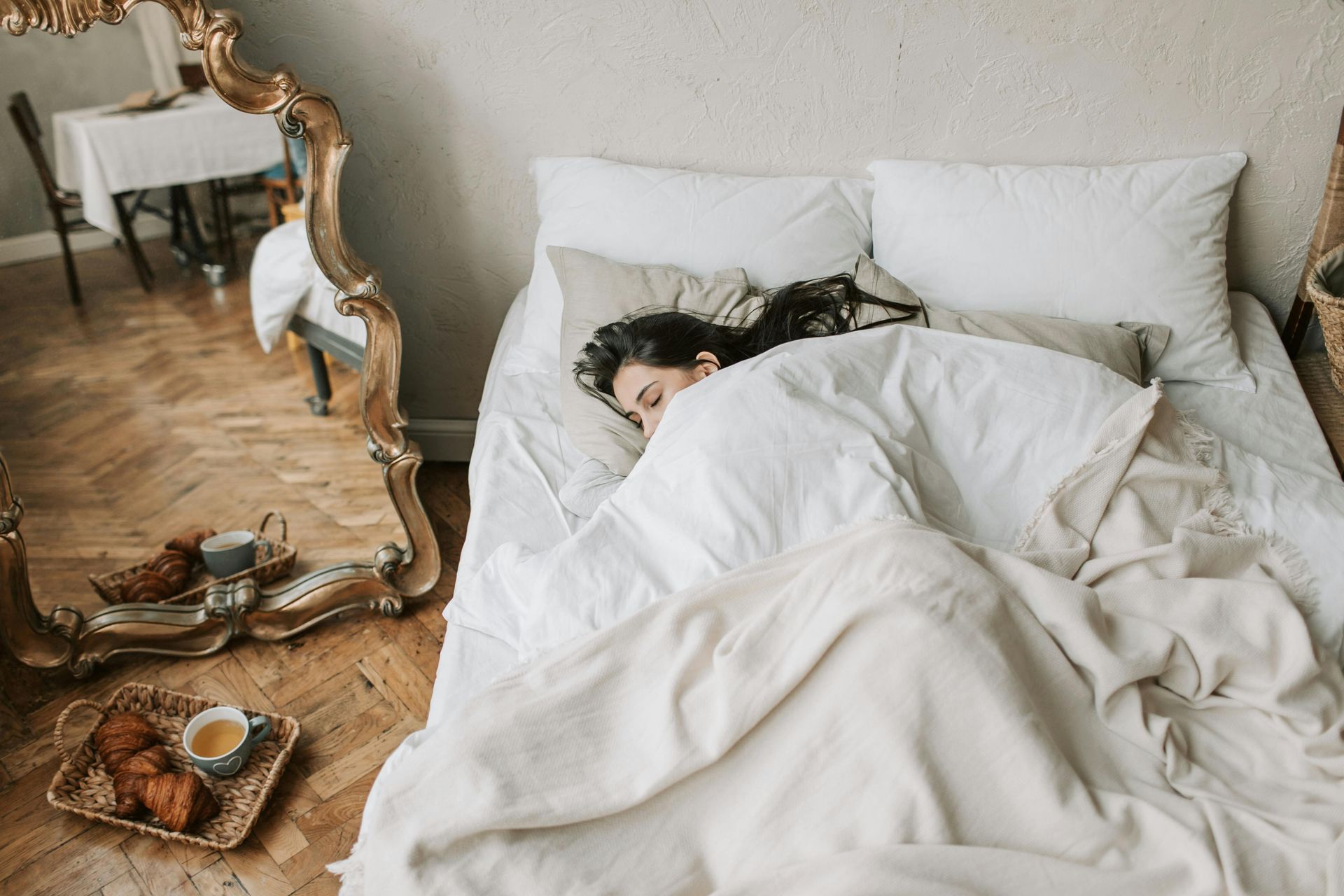 A woman is sleeping on a bed in front of a mirror.