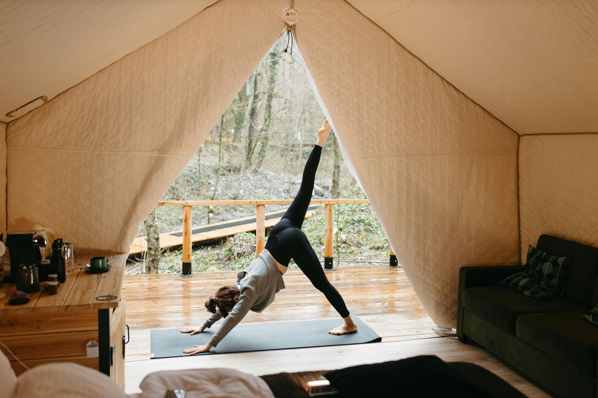A woman is doing yoga on a yoga mat in a tent.
