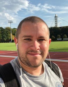 A man wearing headphones is taking a selfie on a track.