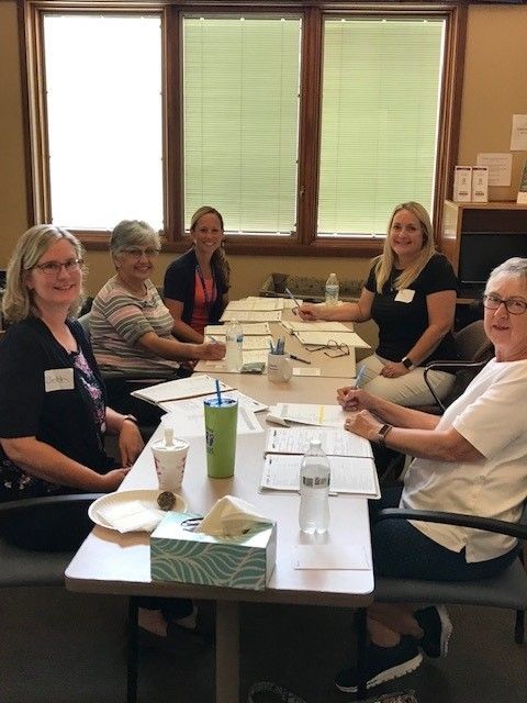 A group of women are sitting around a table in a room.