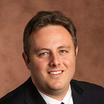 A man in a suit and tie is smiling for the camera.