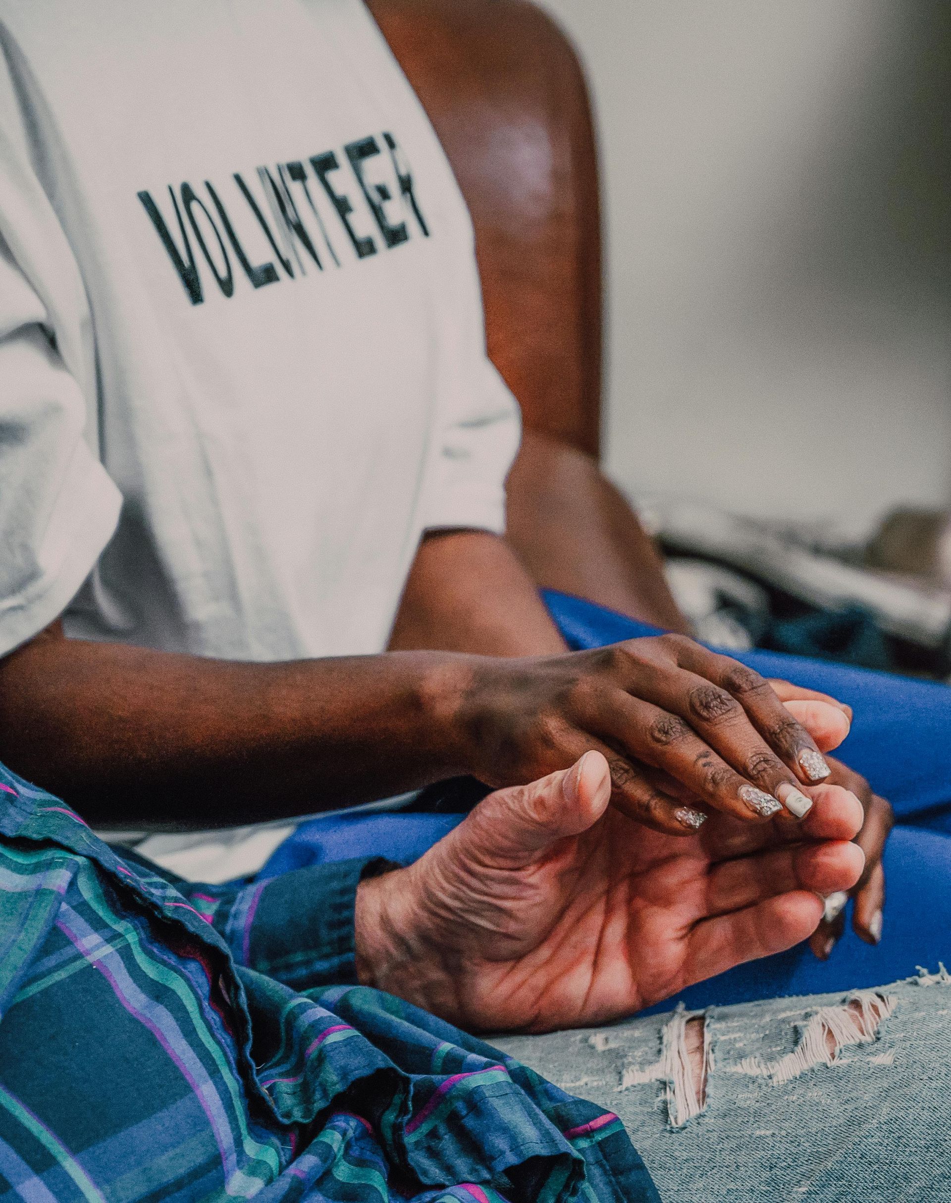 A person wearing a volunteer shirt is holding another person 's hand.