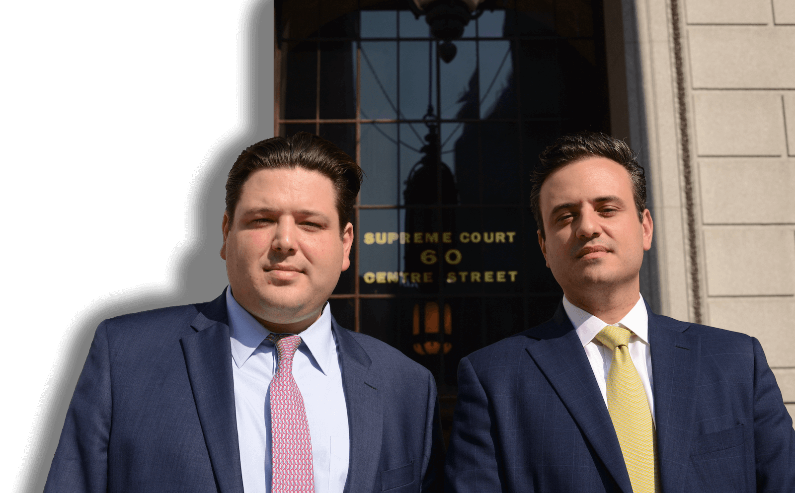 Two men in suits and ties are standing in front of a building.