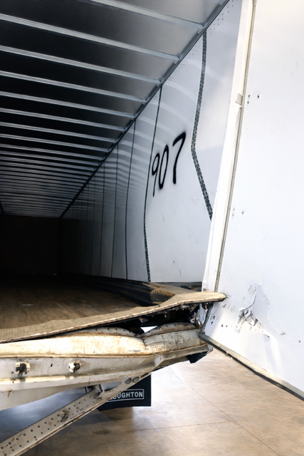 Inside an empty cargo truck, with broken wooden pallets near the open rear door.