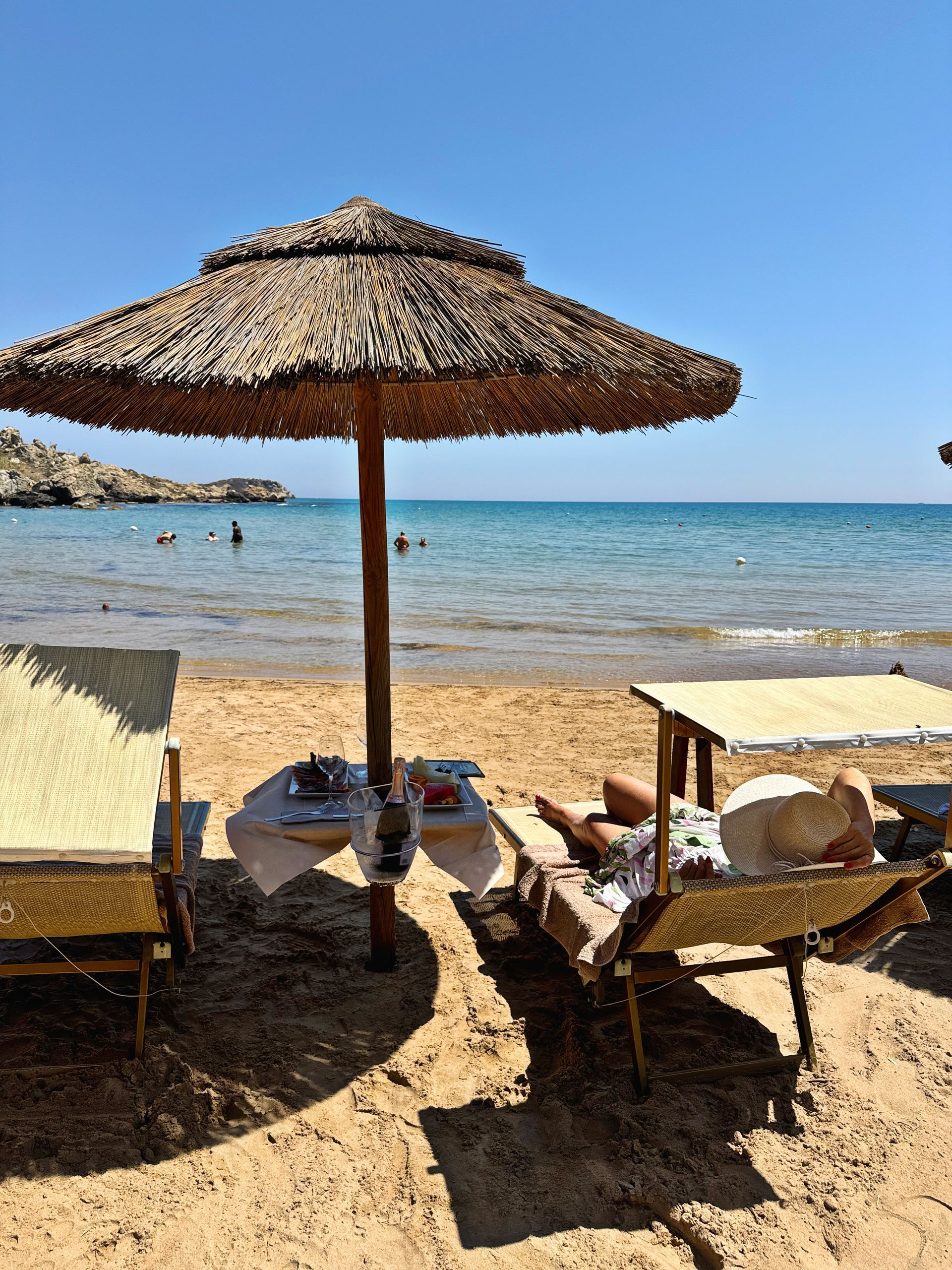 Una persona è sdraiata su una spiaggia sotto un ombrellone.