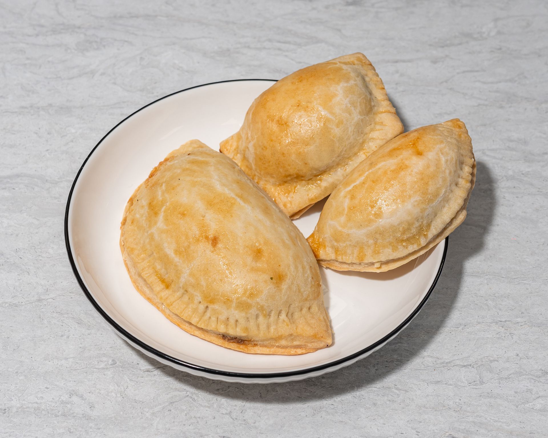 Three golden-brown baked pastries on a white plate.