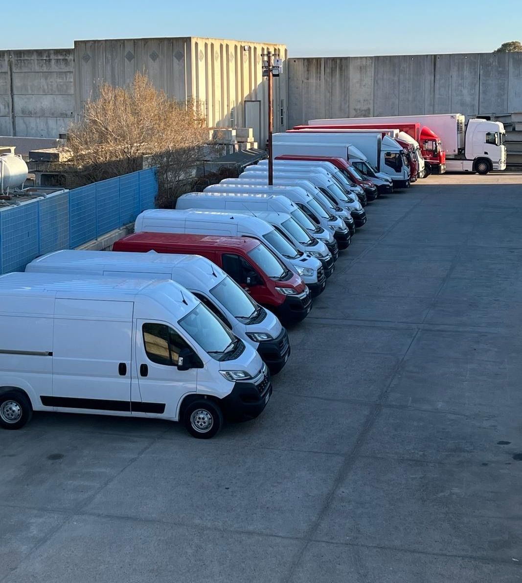 Una fila di furgoni è parcheggiata in un parcheggio, parco mezzi di Grandi