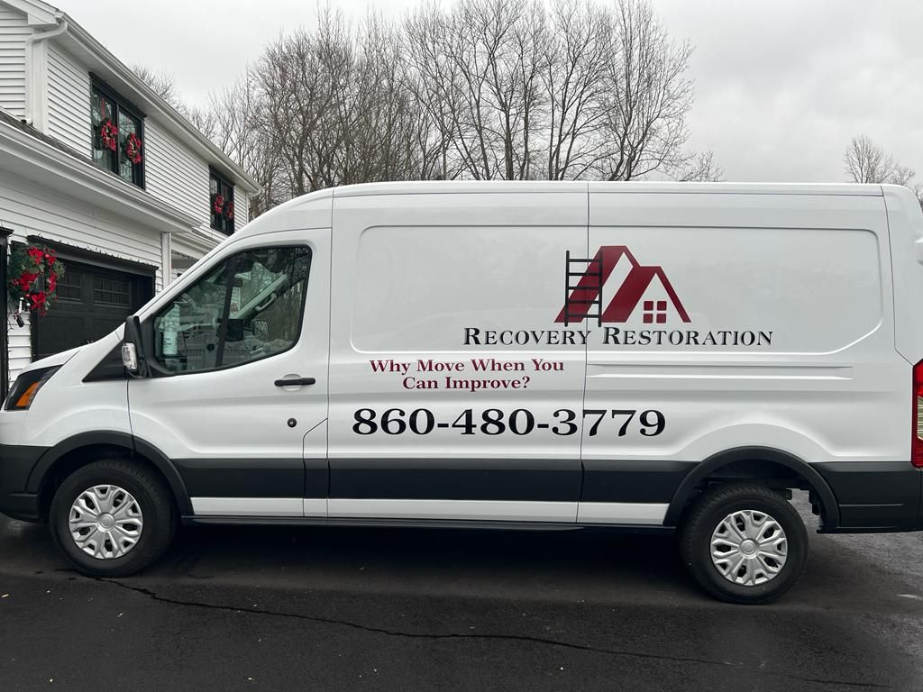 White Recovery Restoration van parked outside a building with holiday wreaths on a snowy day.