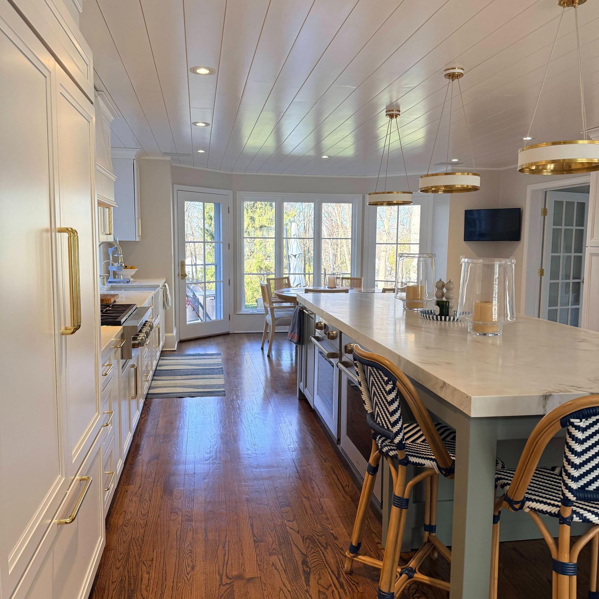 Bright modern kitchen with long island, white cabinets, hardwood floors, and large windows.