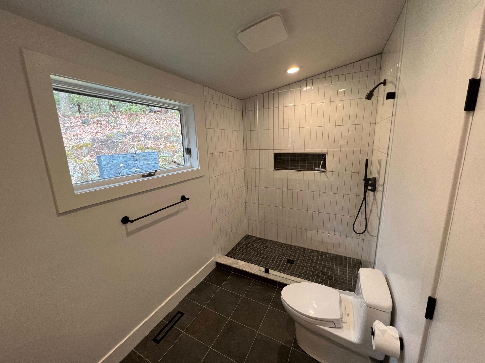 Accessible bathroom with walk-in shower, tiled bench, grab bar, window, and toilet