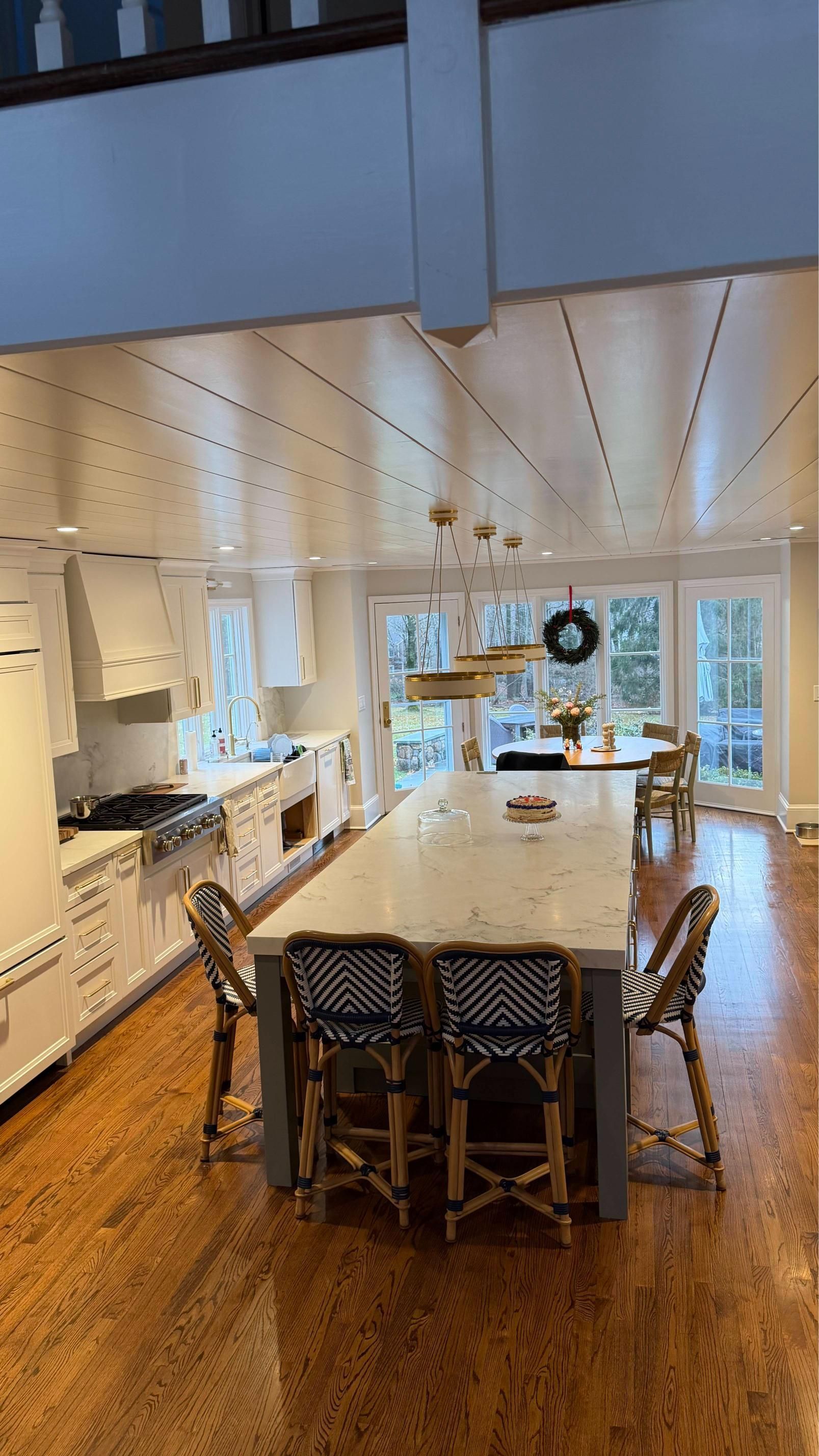 Bright modern kitchen with island, white cabinets, wood floors, and a dining table in the center.